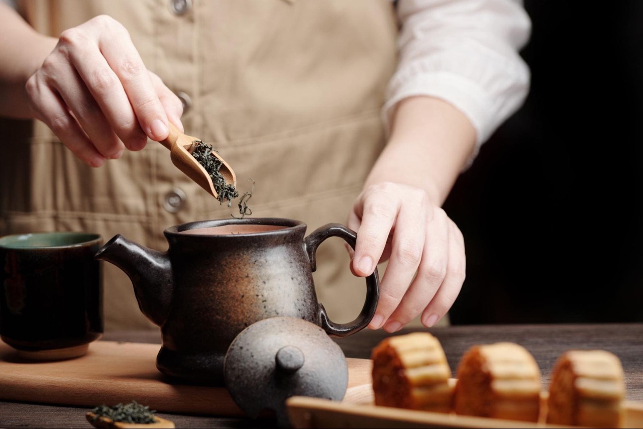 An image showing a person is brewing the tea.