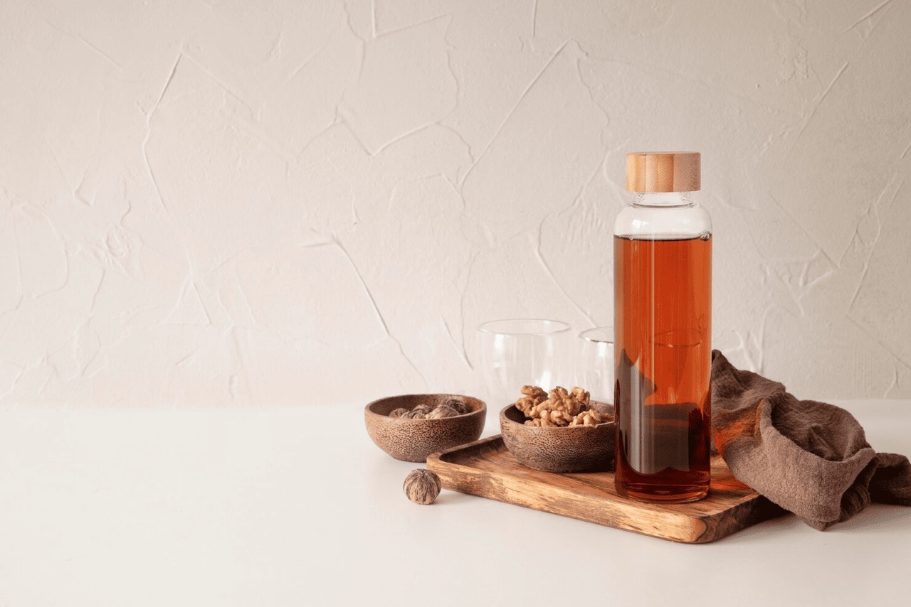 A bottle of tea with cups.
